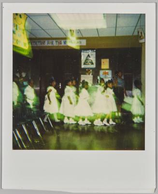 [Profile of children dressed in white and walking in a line]