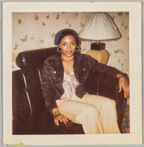 [Woman sitting on black couch wearing a blue hat with blue hoop earrings]
