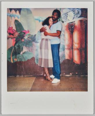 March 85 [Man and woman hugging in front of painted mural on back wall]
