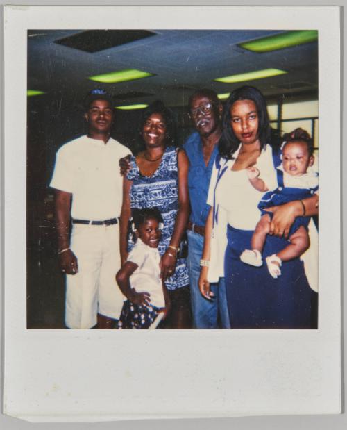 [Family posing, woman on right holding baby on one arm]
