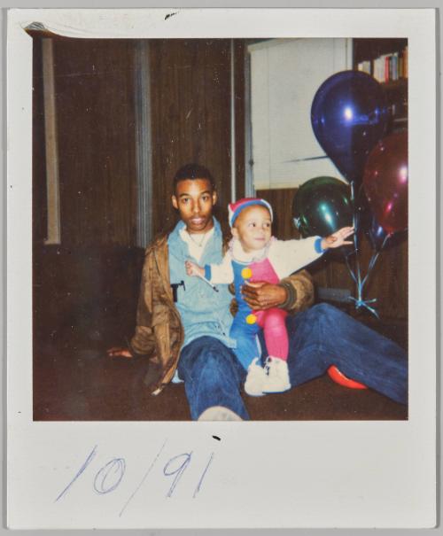 10/91 [Young man holding toddler in clown onesie]
