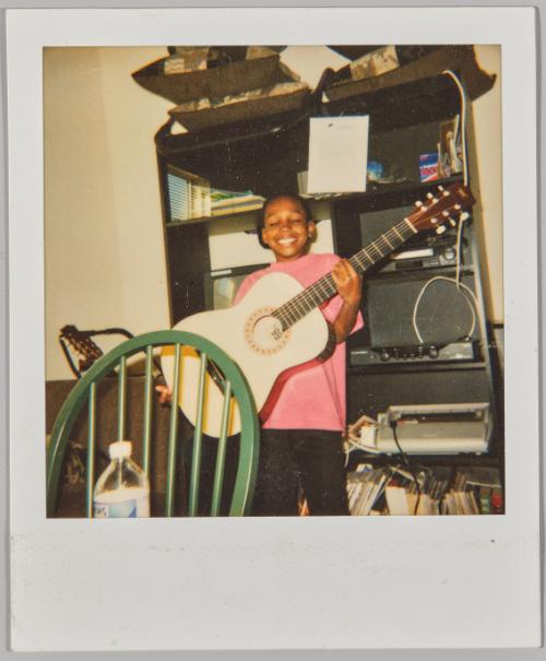 [Little boy holding up a guitar]
