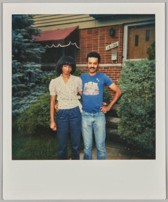 [Couple posing in front of home]
