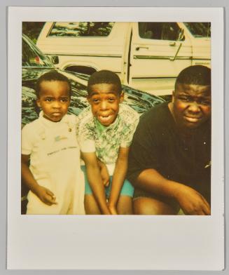 [Three boys sitting on roof of car]
