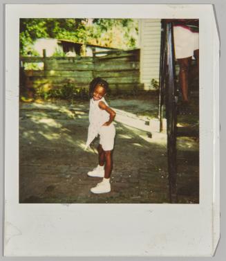 [Girl posing with hands on hips outside near wooden fence]
