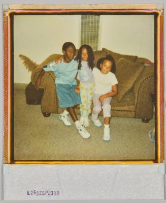 [Boy and two girls with arms around each other, sitting on couch] 
