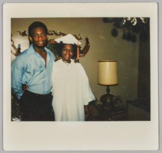 [Adolescent girl and boy, girl wearing white graduation gown and cap]
