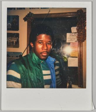 [Man standing in front of mirror with notes attached to frame]
