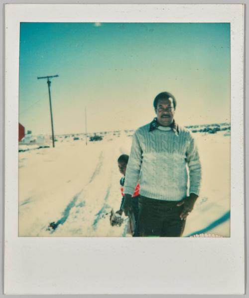 [Man standing in snowy field with boy behind him]
