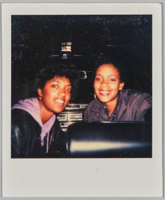[Two young women smiling, woman on right wears a purple hoodie and leather jacket]