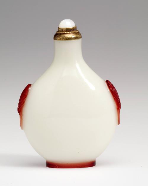 Snuff bottle in glass with red overlay carved with mask and ring handles