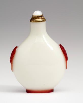Snuff bottle in glass with red overlay carved with mask and ring handles