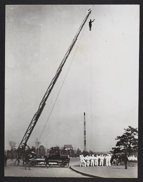 A Japanese man hanging from a large crane.