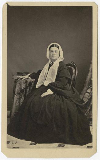 [Woman seated with hand on table]