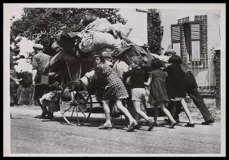 Group of people pushing a loaded kart.