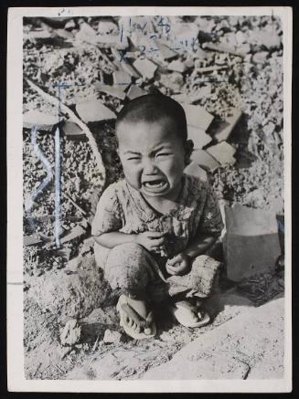 A young boy cries amongst the wreckage of Hiroshima where the clean up operation continues a year after the bomb exploded