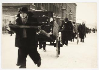 Young boy pulling cart with belongings through the ghetto in winter