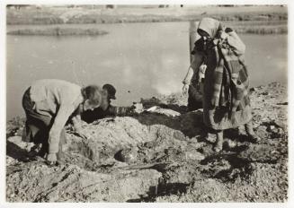 Two women searching ground for food