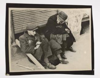 Two men sitting on street