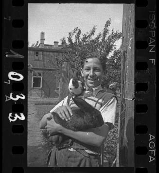 Young man, with two rabbits, beside a vegetable garden