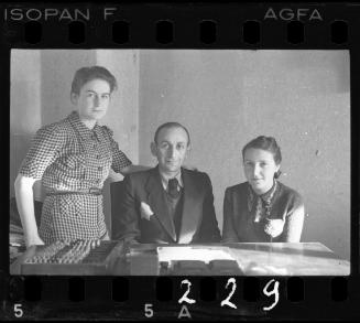 Jewish man and two women [probably members of the ghetto administration] at a table