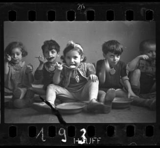 Five children sitting on floor and eating