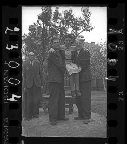 Two young male ghetto residents holding up a sitting girl