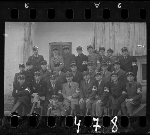 Group portrait of Jewish police; young boy, wearing policeman's hat, sitting in front
