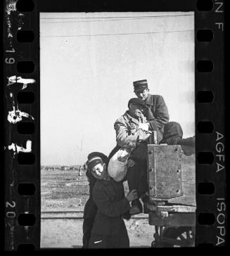Jewish police assisting a man onto a wagon for deportation
