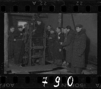 Men in dark coats at a factory