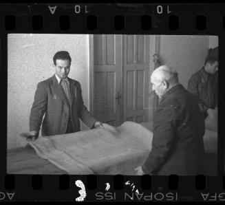 Men holding a bolt of fabric in a workshop in the ghetto
