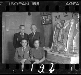 Administrators of the Holzwollefabrik workshop ("ressort") beside a commemorative display, with a portrait of Mordechai Chaim Rumkowski