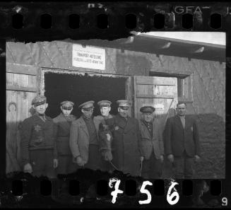 Workers of the Transport Department standing in the entrance to a horse stable