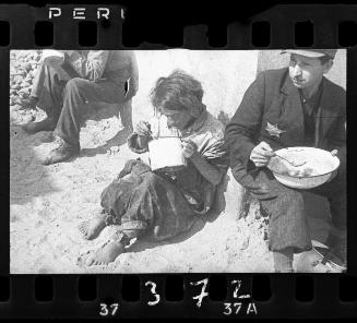 Man and woman eating from pot and pail on street corner