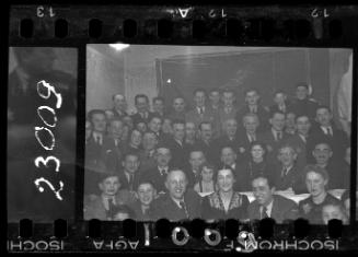 Large group of men, women and children in formal attire [probably members of the Judenrat, the Jewish Council, and their families]