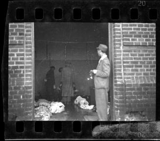 Ghetto officials standing among bodies in the morgue