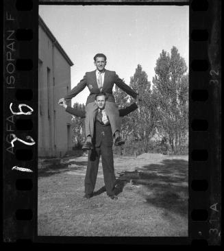 Two ghetto male residents, one sitting on the shoulders of the other