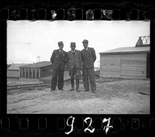 Three Jewish policemen standing beside a railroad track