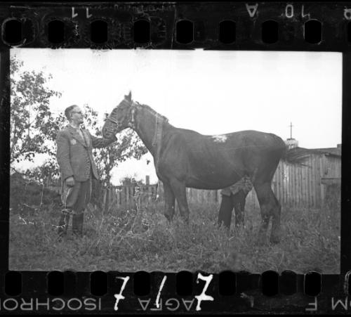 Dr. Kagan, hospital administrator, posing with a horse in a yard