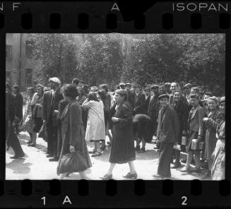 Large group of residents walking in the streetm some carrying pails and other belongings