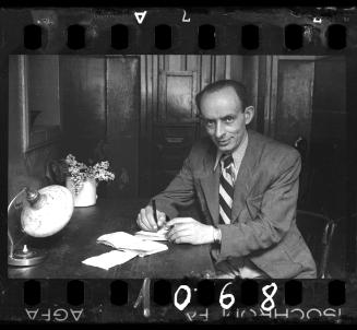 Member of the ghetto administration sitting at a table and writing in a notebook