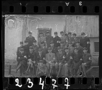 Group portrait of Jewish police; young boy, wearing policeman's hat, sitting in front