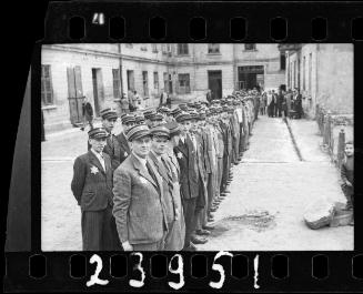 Jewish police, standing in a line, in a courtyard in the ghetto