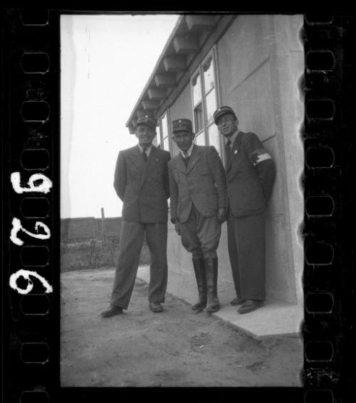 Three Jewish policemen standing outside a shack