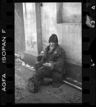Elderly man sitting on the street with feet bundled in rags
