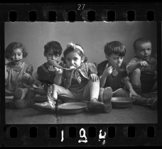 Five children sitting on floor and eating
