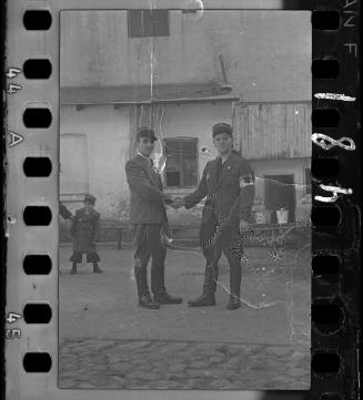 Two Jewish policemen shaking hands with a young boy, wearing policeman's hat