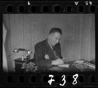 Administrator sitting at a desk, writing on a notepad
