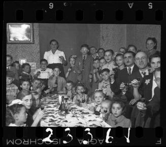 Children and parents gathered around the table at a children's party
