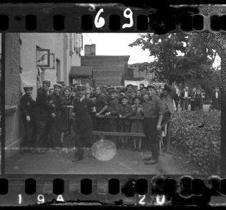 Jewish police guarding ghetto residents behind a wooden fence
